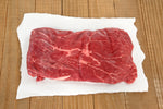 Raw beef on a piece of paper on a wooden surface